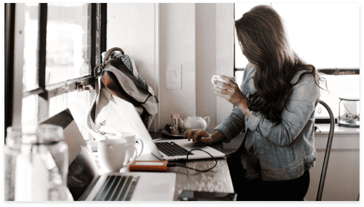 image of an employee sitting at her desk with some coffee
